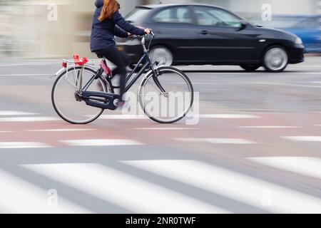 immagine sfocata del movimento di una giovane donna con una bicicletta in movimento in città Foto Stock