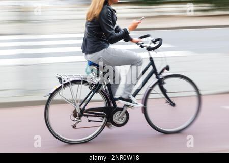 immagine sfocata del movimento di una giovane donna con una bicicletta in movimento in città Foto Stock