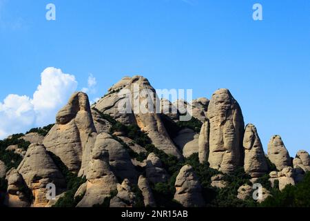 una montagna di picco di formazioni rocciose finger-like vista contro il cielo blu con poche nuvole bianche in un angolo Foto Stock