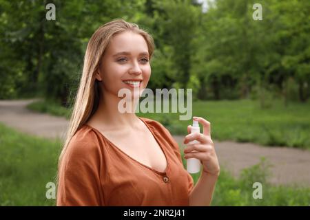 Donna che usa repellente per insetti nel parco. Prevenzione punture di zecca Foto Stock