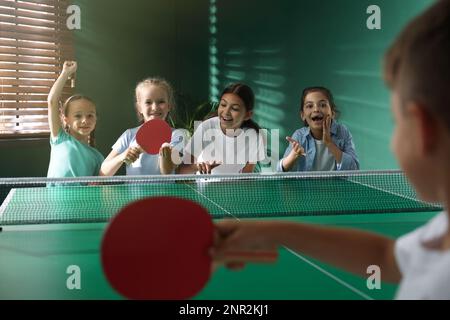 Bambini felici e carini che giocano a ping pong al coperto Foto Stock