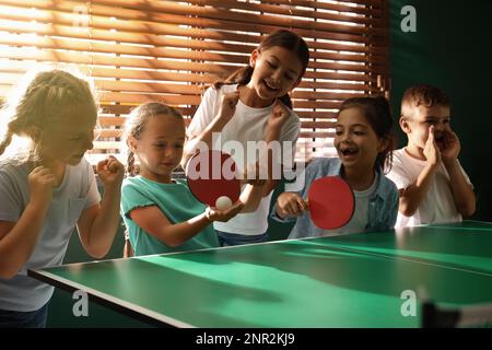 Bambini felici e carini che giocano a ping pong al coperto Foto Stock