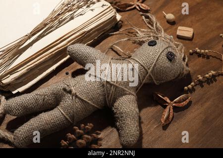 Bambola voodoo femminile con spille circondate da oggetti cerimoniali su sfondo di legno, primo piano Foto Stock