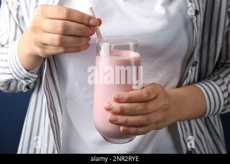 Donna con un bicchiere di frullato gustoso, primo piano Foto Stock