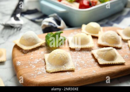 Ravioli crudi con basilico su asse di legno, primo piano Foto Stock