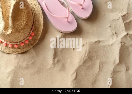 Cappello di paglia e infradito sulla sabbia, piatto. Spazio per il testo Foto Stock