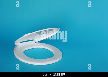 Nuovo sedile in plastica per gabinetto su sfondo azzurro, spazio per testo Foto Stock