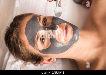 Bella giovane donna che applica maschera viso il suo viso Foto Stock