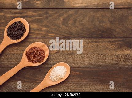 Cucchiai di legno con tre tipi diversi di riso tavola di legno Foto Stock