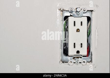 Presa di corrente pericolosa con cavi esposti senza coperchio di sicurezza della piastra a parete in plastica. Concetto di pericolo per la sicurezza della presa elettrica precedente con spazio di copia. Foto Stock