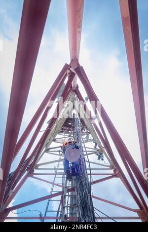 Tecnico non riconosciuto che sale su una torre di telecomunicazioni. Foto Stock