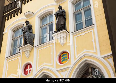 Vecchio 18th ° secolo giallo con finitura bianca facciata edificio architettonico con sculture in bronzo, Tallinn, Estonia. Foto Stock