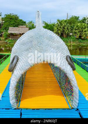 La splendida vista del tunnel assomiglia a pesci grandi fatti da molte bottiglie di plastica chiara usate sul ponte pedonale sopra il fiume. Utilizzando vecchi flaconi di plastica t Foto Stock