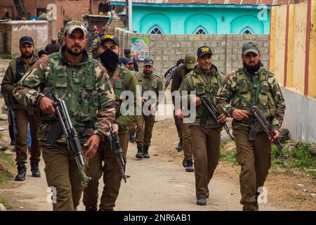 Srinagar, India. 25th Feb, 2023. I poliziotti indiani camminano verso il sito di attacco dove Sanjay Sharma a Kashmiri la guardia di sicurezza della banca indù è stata uccise da sospettati militanti a Pulwama Sud del Kashmir amministrato dagli indiani. La polizia ha detto che i militanti sospetti hanno aperto il fuoco su Sanjay Sharma mentre era sulla sua strada verso un mercato locale nel distretto di Pulwama del villaggio di Achan. Credit: SOPA Images Limited/Alamy Live News Foto Stock