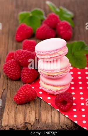 Biscotti rosa al macaron di lamponi su tavole di legno scuro Foto Stock