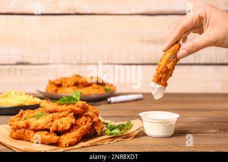 Donna che immerga gustoso nocciolo in salsa su tavola di legno Foto Stock