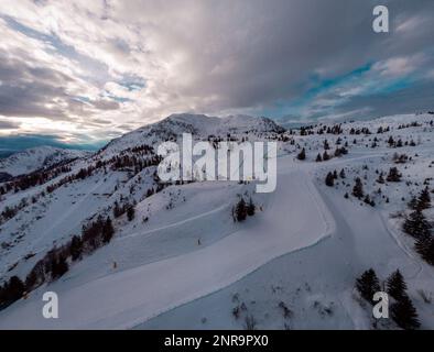 Panorama aereo dei droni della stazione sciistica di Zoncolan nel nord Italia in una nuvolosa giornata invernale. Montagne visibili intorno, buona visibilità. Foto Stock