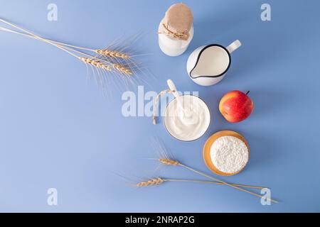 Splendido sfondo festivo per la vacanza ebraica di Shavuot con varie prelibatezze tradizionali con una copia dello spazio. sfondo blu Foto Stock