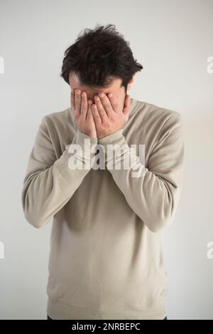 Uomo che nasconde il viso in mano Foto Stock