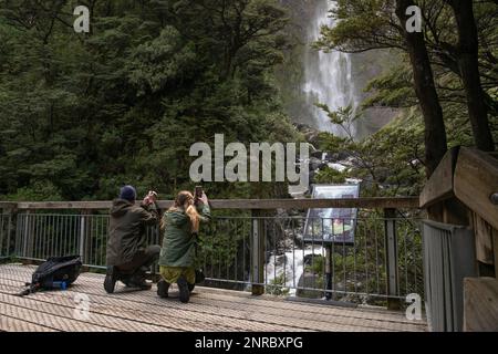 Un paio di escursionisti che scattano foto al telefono sulla piattaforma di osservazione a Devils punchbowl cade in Nuova Zelanda. Foto Stock