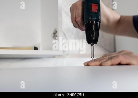 montaggio di mobili. avvitamento delle viti da lavoro con un trapano a batteria Foto Stock