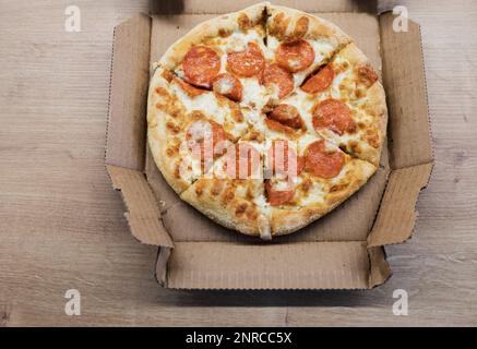 Pizza in una scatola di cartone sullo sfondo. Primo piano. Vista dall'alto. Foto Stock