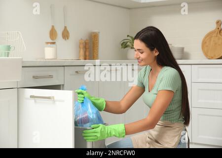 Donna che prende il sacchetto di immondizia dal cestino nel paese Foto Stock