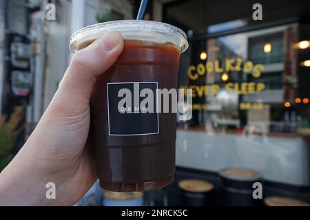 Primo piano tenendo la mano Iced Black americano in una tazza di plastica da togliere Foto Stock