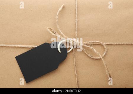 Pacco avvolto in carta kraft con tag come sfondo, primo piano Foto Stock