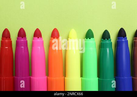 Set di penne con punta in feltro su sfondo verde chiaro, giacitura piatta Foto Stock