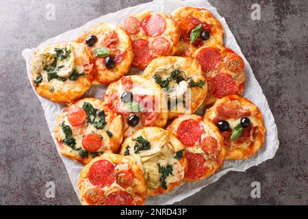 Pizzette mini pizze italiane o pizze primo piano su pergamena sul tavolo. Vista orizzontale dall'alto Foto Stock