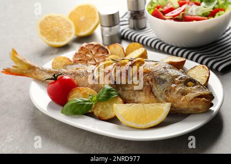 Gustoso persico arrosto fatto in casa con decorazione su tavolo grigio. Pesce di fiume Foto Stock
