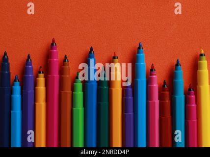 Set di penne con punta in feltro su sfondo arancione, giacitura piatta Foto Stock