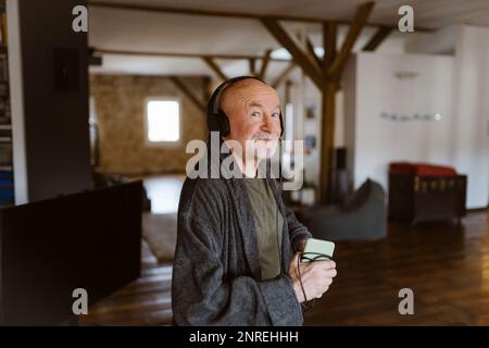 Ritratto dell'uomo anziano che ascolta la musica attraverso le cuffie a casa Foto Stock