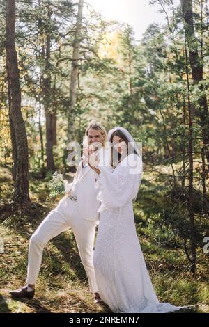 Sposa felice e sposo tenendo le mani mentre godendo nella foresta Foto Stock