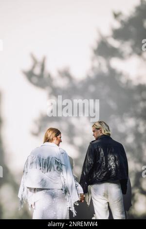 Vista posteriore della sposa e dello sposo appena sposati che tengono le mani mentre si guardano l'un l'altro il giorno del matrimonio Foto Stock