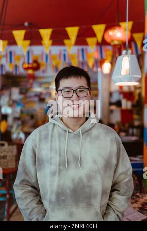 Ritratto di un giovane sorridente che indossa una felpa con cappuccio al ristorante Foto Stock