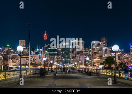Sydney, Australia - 16 aprile 2022: Skyline illuminato della città di Sydney visto da Pyrmont Bridge attraverso Darling Harbour di notte Foto Stock