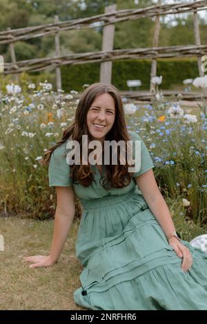 Ragazza in vestito verde seduta in un giardino inglese in primavera Foto Stock