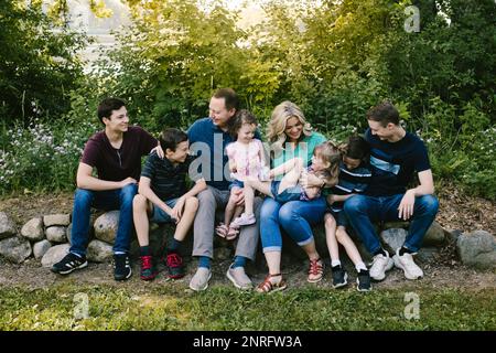 Il gruppo di famiglia ride insieme nella foresta verde con molti bambini Foto Stock