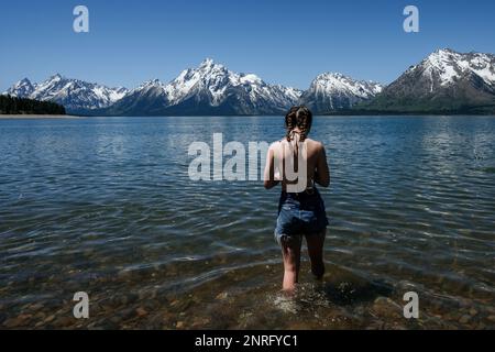 Ragazza che cammina nel lago il giorno di sole Foto Stock