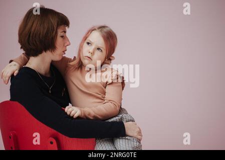 donna in vestito nero che tiene la figlia Foto Stock
