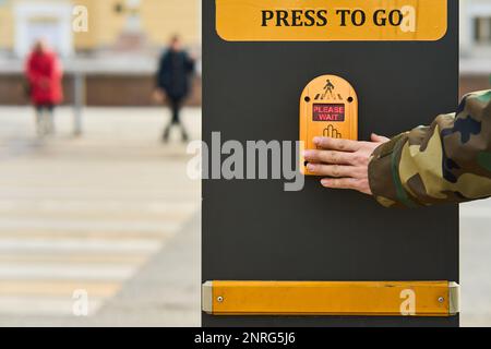 Una mano di un uomo preme un sensore del semaforo per accendere il verde Foto Stock