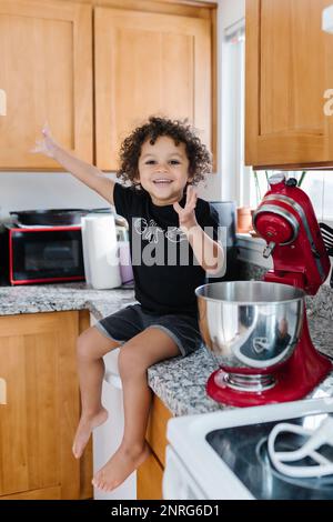 Eccitati a celebrare la cottura biraciale dei bimbi e seduti sul bancone Foto Stock