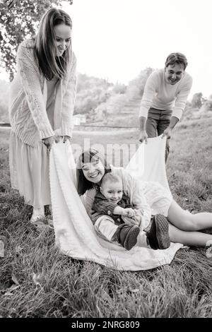 Immagine B&W di famiglia felice con due bambini che giocano sull'erba Foto Stock