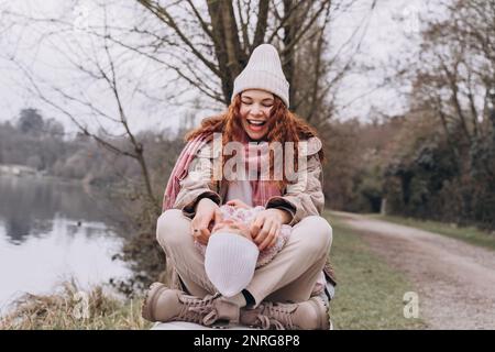 la mamma e il bambino ricci si siedono in un parco nebbioso vicino al fiume che gioca. Foto Stock