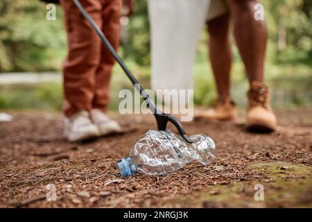 Primo piano del bambino che raccoglie la bottiglia di plastica all'aperto in natura, spazio di copia Foto Stock