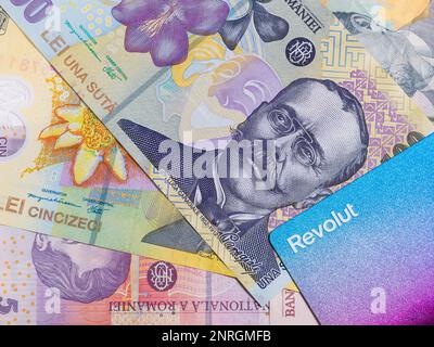 Carta di credito o di debito Revolut e molte banconote rumene su sfondo nero. Concetto di valuta rumena. Foto Stock