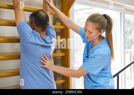 Fisioterapista femminile che assiste l'uomo anziano nell'esercizio presso il centro di riabilitazione Foto Stock