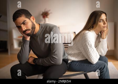 Un giovane arabo triste e infelice ignora la donna europea seduta sul divano da una parte all'altra Foto Stock